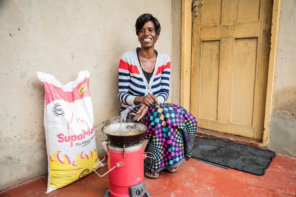 Kvinnan använder Supamoto och Emerging Cookstoves spisen