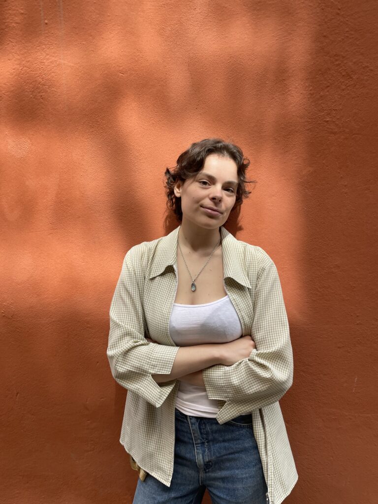 A woman with short brown hair standing in front of a red wall