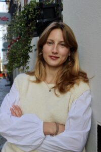 En kvinna i vit blus och rödblont hår.