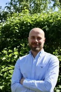 En man som står framför en buske iförd skjorta