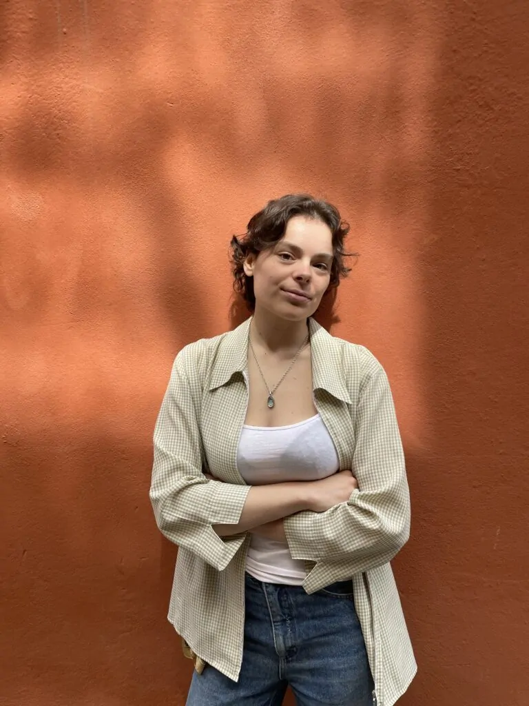 A woman with short brown hair standing in front of a red wall