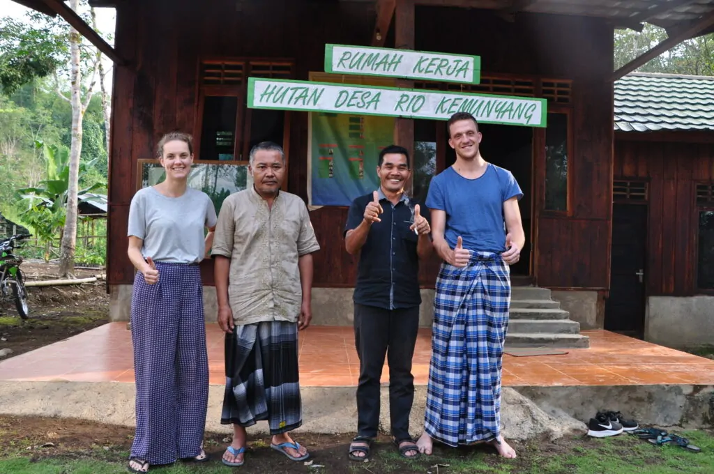 Four people standing in front of a house and smiling.